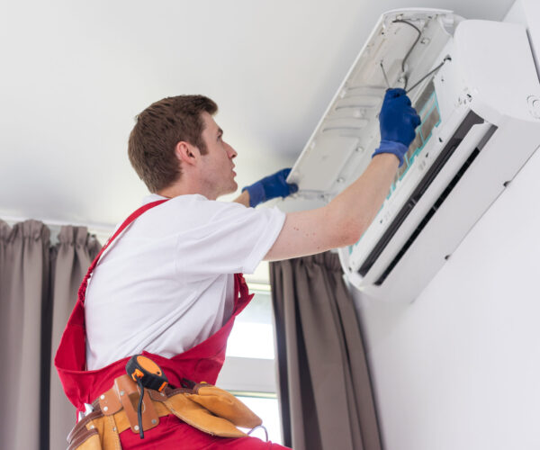 Professional technician maintaining modern air conditioner indoors